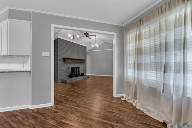 unfurnished living room featuring baseboards, an inviting chandelier, crown molding, a fireplace, and dark wood-type flooring