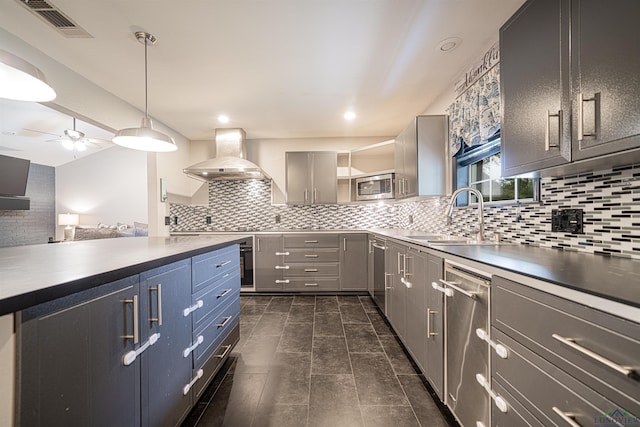 kitchen featuring gray cabinetry, backsplash, wall chimney range hood, sink, and stainless steel appliances