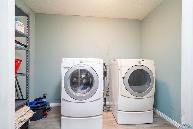 laundry area featuring washer and dryer, a textured ceiling, and light wood-type flooring