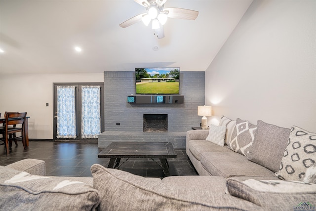 living room with a brick fireplace, vaulted ceiling, and ceiling fan