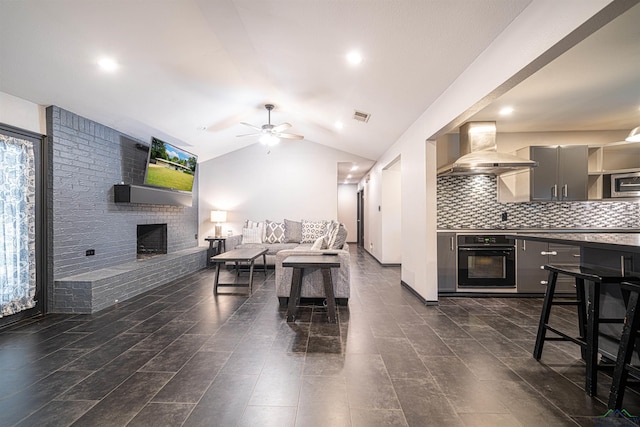 living room featuring a brick fireplace, ceiling fan, and lofted ceiling