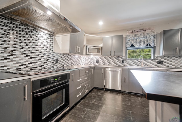 kitchen with sink, wall chimney exhaust hood, backsplash, gray cabinets, and black appliances