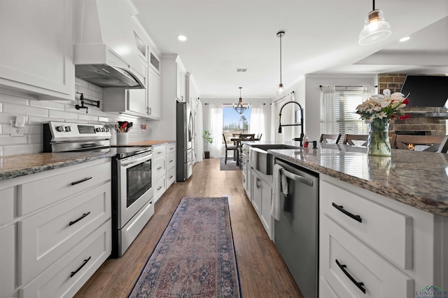 kitchen featuring white cabinetry, decorative light fixtures, stainless steel appliances, and custom range hood