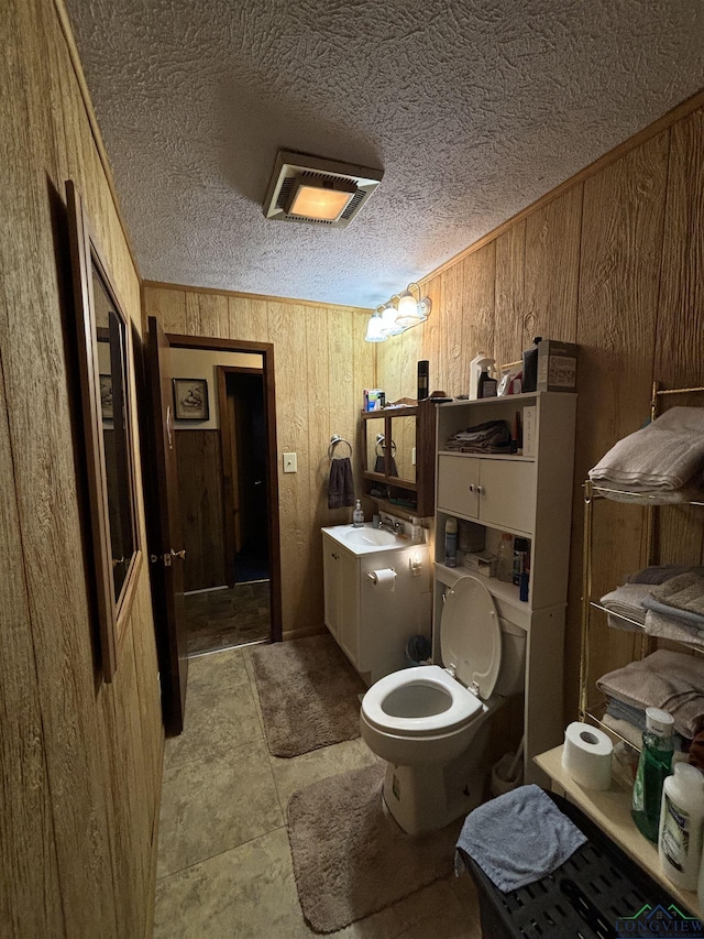 bathroom with wood walls, vanity, and toilet