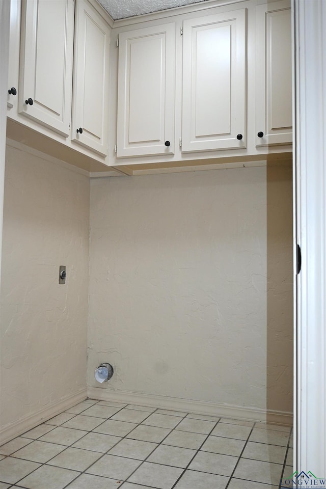 811 Georgia Ln, Longview, TX 75604 - laundry area featuring hookup for an electric dryer, cabinet space, and light tile patterned flooring