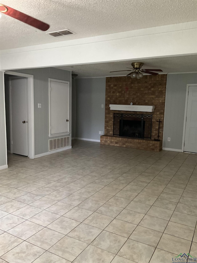 unfurnished living room featuring ceiling fan, light tile patterned floors, a textured ceiling, and a brick fireplace