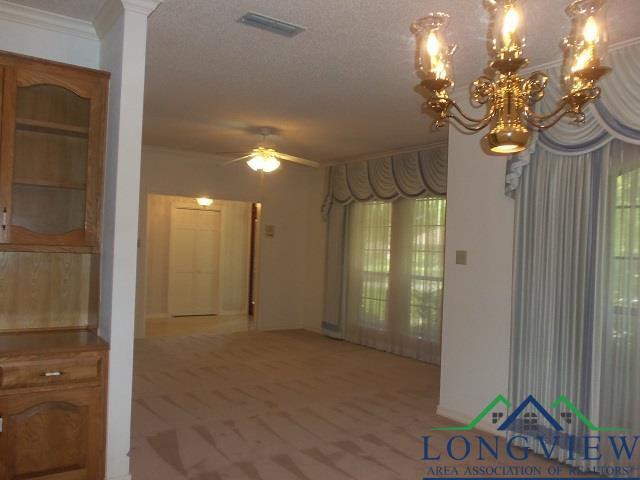 404 Moccasin Trl, Kilgore, TX 75662 - hall featuring ornamental molding, light colored carpet, a chandelier, healthy amount of natural light, and a textured ceiling