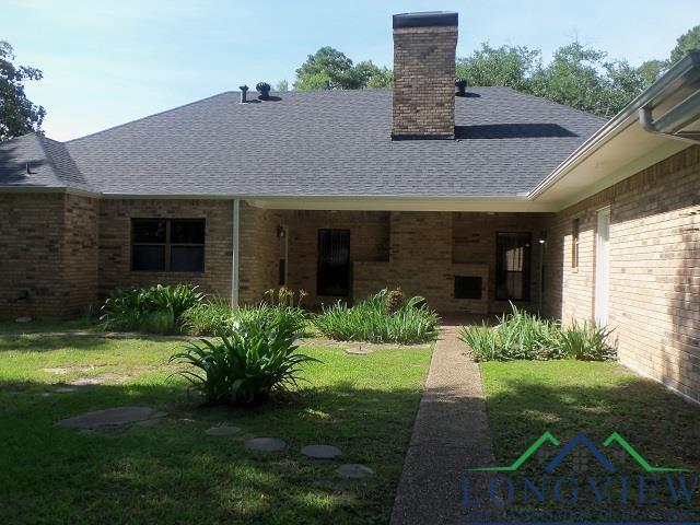 404 Moccasin Trl, Kilgore, TX 75662 - rear view of house with a yard, a chimney, brick siding, and roof with shingles