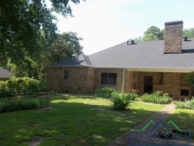 404 Moccasin Trl, Kilgore, TX 75662 - rear view of house with a yard, a shingled roof, a chimney, and brick siding