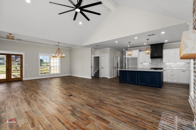 kitchen featuring tasteful backsplash, white cabinetry, a center island with sink, and hanging light fixtures