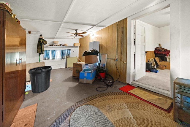 interior space featuring ceiling fan, concrete flooring, and wood walls