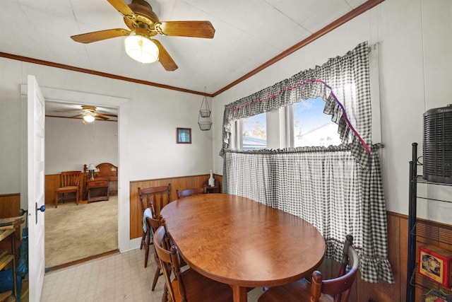 dining space featuring crown molding, ceiling fan, and wood walls