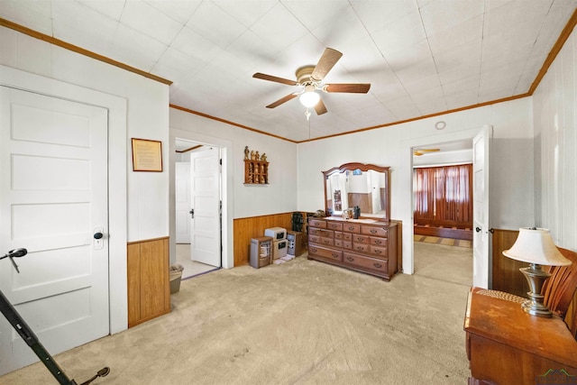 bedroom featuring crown molding, light colored carpet, wooden walls, and ceiling fan