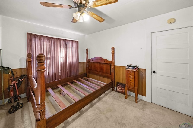 bedroom with light carpet, ceiling fan, and wood walls