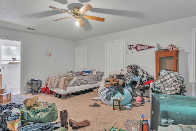 carpeted bedroom featuring a ceiling fan and visible vents