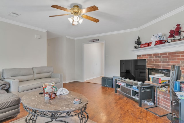 living area with baseboards, visible vents, a ceiling fan, wood finished floors, and crown molding