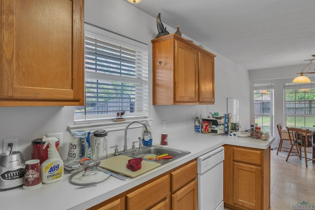 kitchen featuring light countertops, dishwasher, a sink, a peninsula, and brown cabinetry