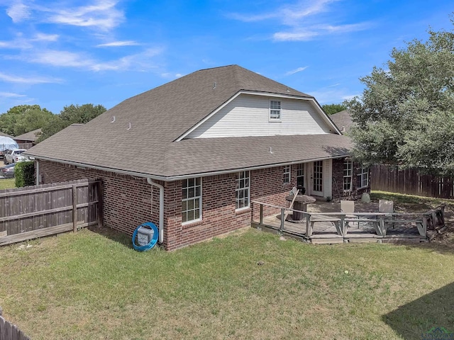 rear view of property featuring fence, a shingled roof, brick siding, and a yard