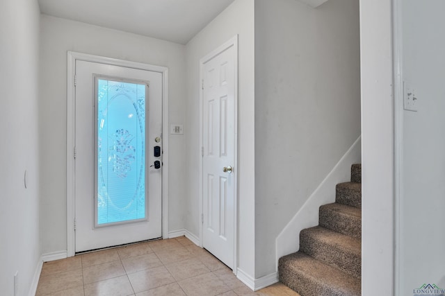 foyer entrance with light tile patterned flooring, baseboards, and stairs