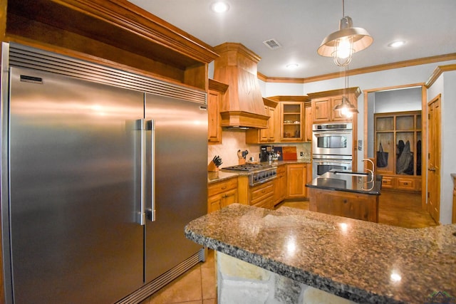 1326 Hermitage Ct, Tyler, TX 75703 - kitchen featuring stainless steel appliances, custom range hood, an island with sink, light tile patterned floors, and hanging light fixtures