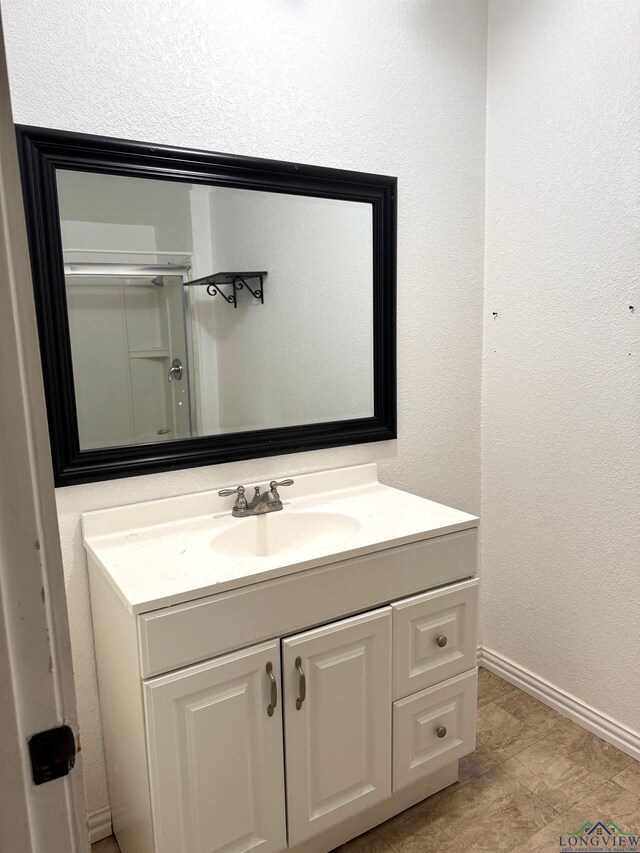 308 E 14th St, Mount Pleasant, TX 75455 - bathroom featuring a shower with door, baseboards, a textured wall, and vanity