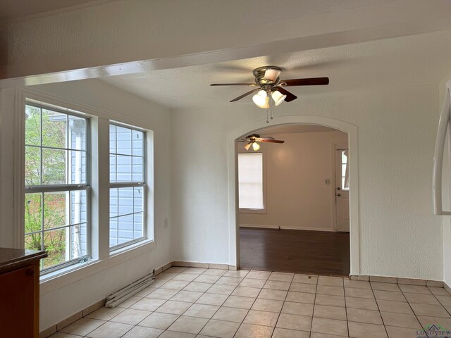 308 E 14th St, Mount Pleasant, TX 75455 - spare room with a textured wall, light tile patterned flooring, arched walkways, and ceiling fan