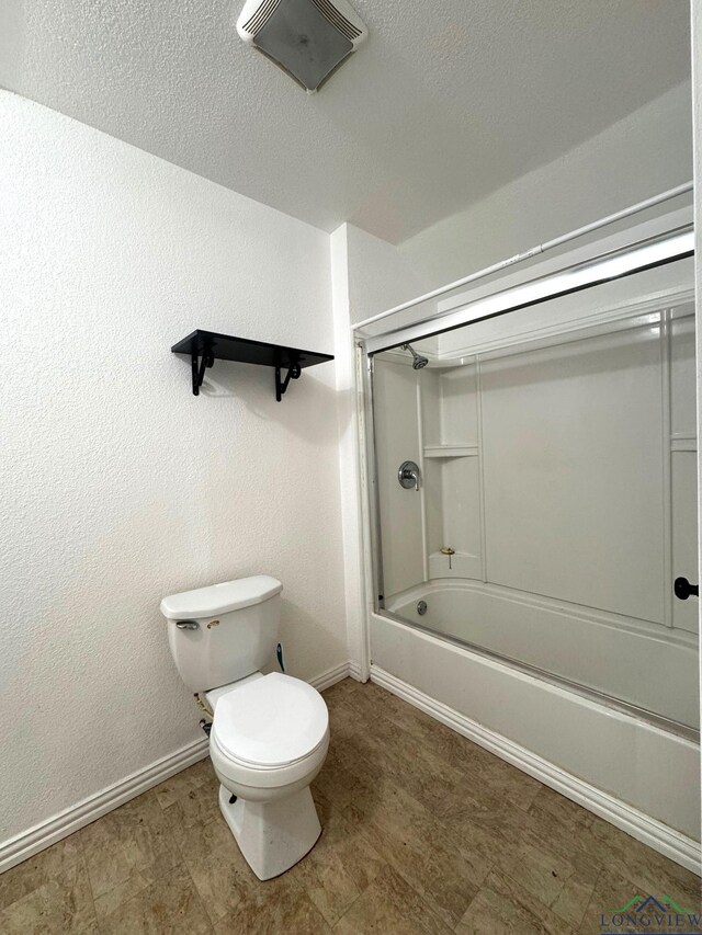 308 E 14th St, Mount Pleasant, TX 75455 - full bath featuring a textured ceiling, baseboards, toilet, enclosed tub / shower combo, and a textured wall