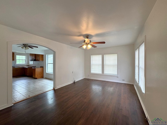 308 E 14th St, Mount Pleasant, TX 75455 - unfurnished living room featuring arched walkways, baseboards, wood finished floors, and a ceiling fan