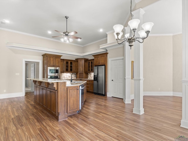 kitchen with stainless steel appliances, crown molding, decorative light fixtures, decorative backsplash, and a center island with sink