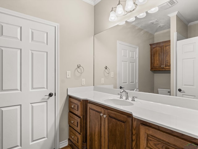 bathroom with vanity, toilet, and crown molding