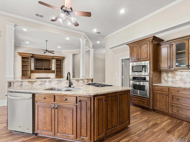 kitchen with sink, stainless steel appliances, decorative columns, crown molding, and decorative backsplash