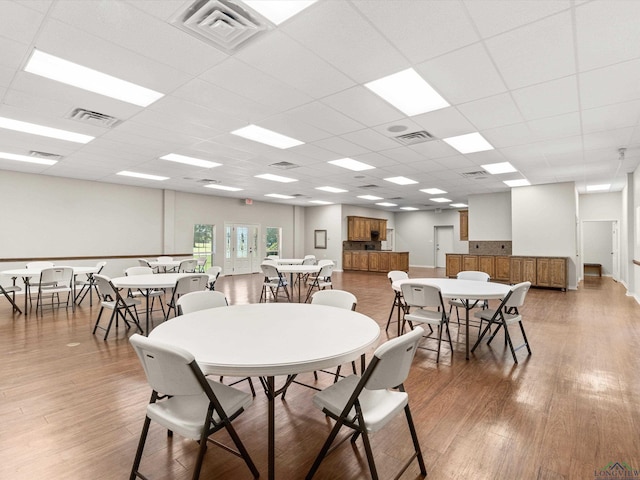 dining space with a drop ceiling and hardwood / wood-style flooring