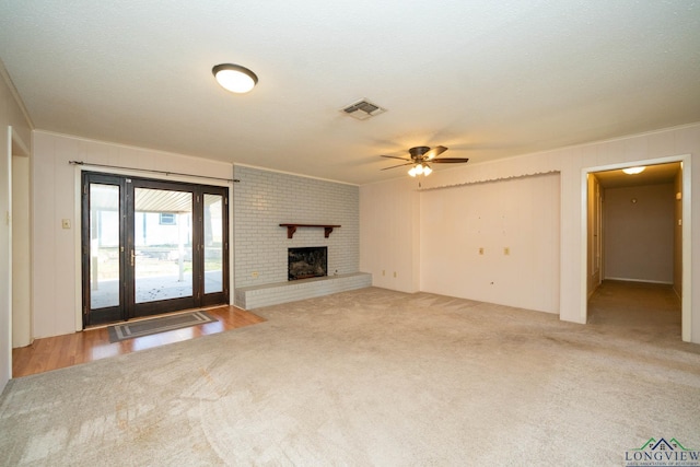 unfurnished living room featuring carpet floors, a brick fireplace, and ceiling fan