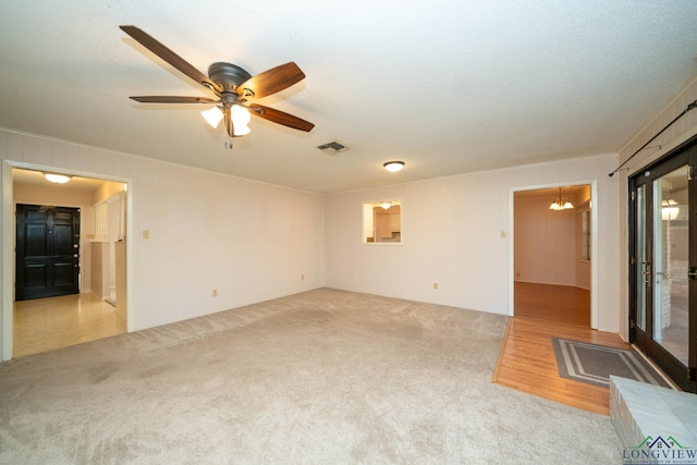 unfurnished living room with light carpet, a textured ceiling, and ceiling fan