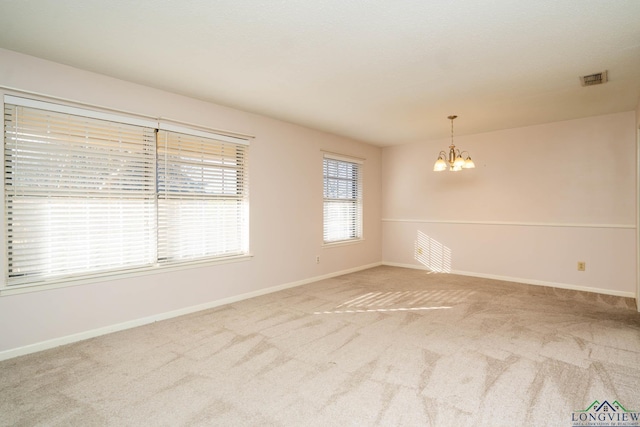 unfurnished room with carpet flooring and an inviting chandelier