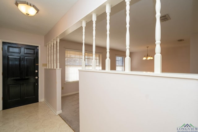 entryway featuring a notable chandelier and light carpet