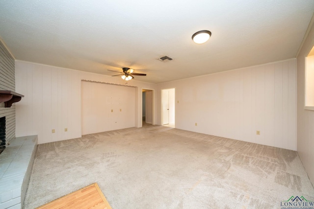 unfurnished living room featuring carpet flooring, ceiling fan, a fireplace, and wooden walls