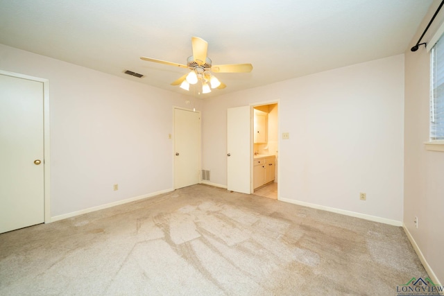 unfurnished bedroom featuring ceiling fan, light colored carpet, and connected bathroom