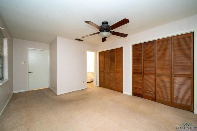 unfurnished bedroom with multiple closets, ceiling fan, and light carpet