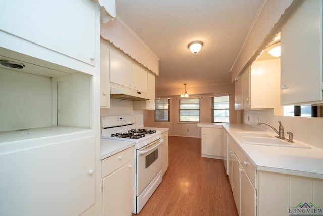 kitchen featuring white cabinets, pendant lighting, sink, and gas range gas stove