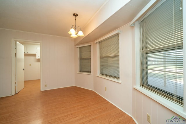 unfurnished room with light hardwood / wood-style flooring, crown molding, and a notable chandelier