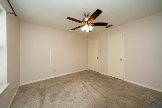 unfurnished bedroom with ceiling fan, light colored carpet, and a textured ceiling