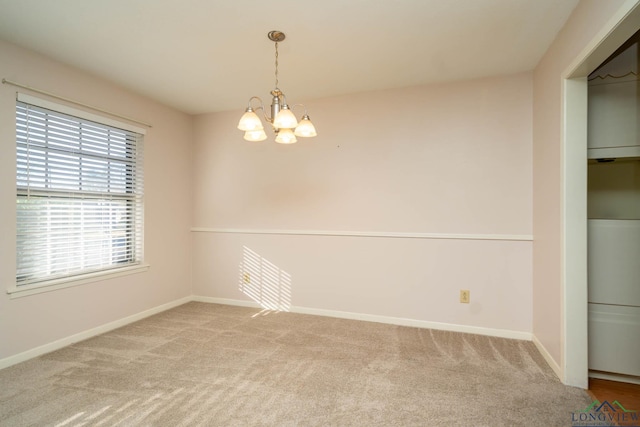 carpeted empty room with a notable chandelier