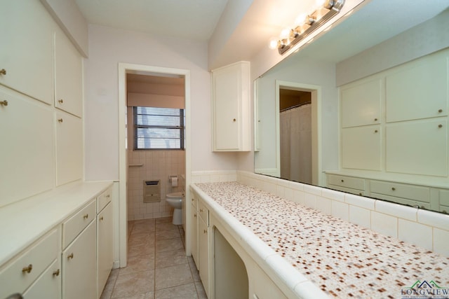 bathroom with tile patterned floors, vanity, tile walls, and toilet