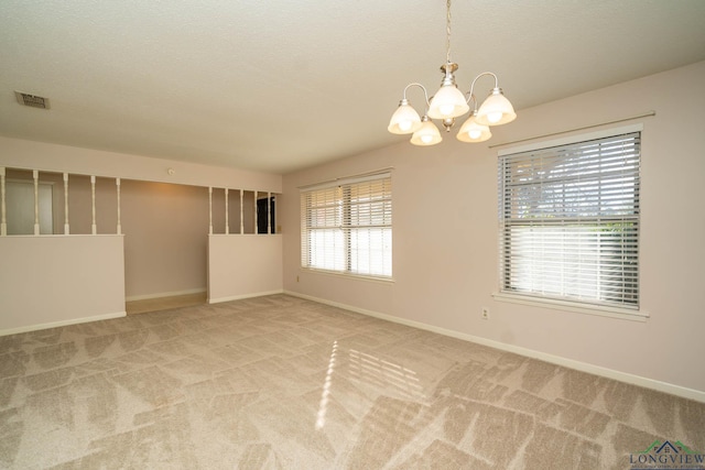 spare room with carpet and a chandelier