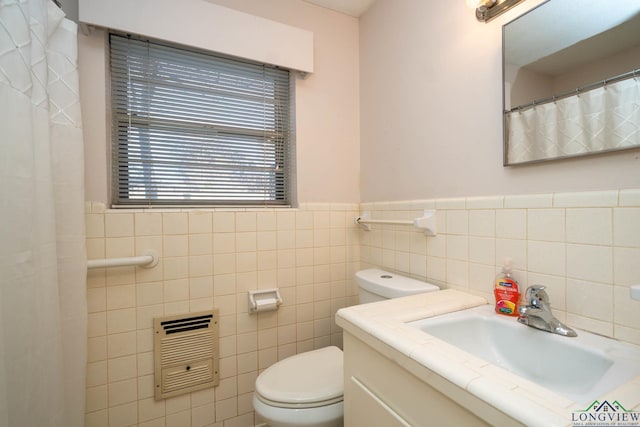 bathroom with vanity, heating unit, toilet, and tile walls