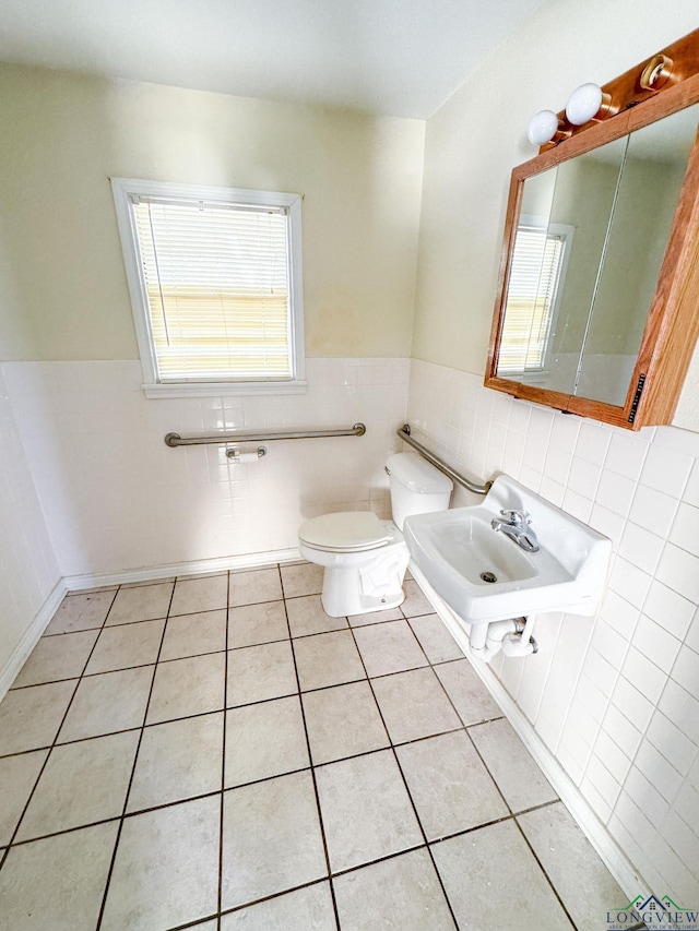 bathroom with toilet, sink, and tile patterned flooring