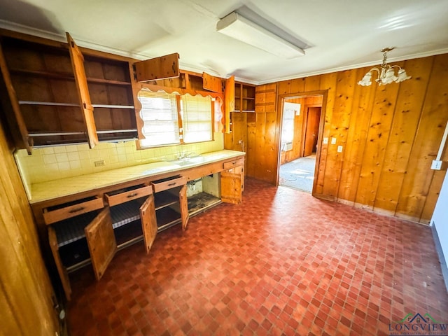 kitchen featuring a chandelier, crown molding, pendant lighting, and wood walls