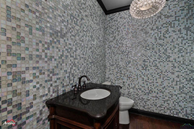 bathroom featuring hardwood / wood-style floors, vanity, crown molding, toilet, and tile walls