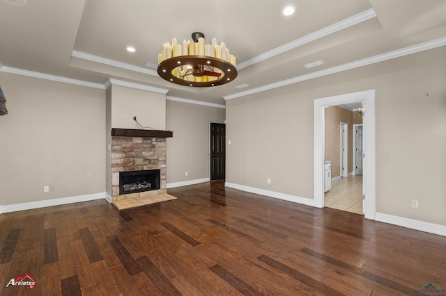 unfurnished living room with a chandelier, a stone fireplace, ornamental molding, and a tray ceiling